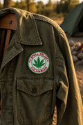 THC Columbian Patch featuring a green cannabis leaf and red embroidered lettering displayed on the chest of a vintage olive-green field jacket outdoors