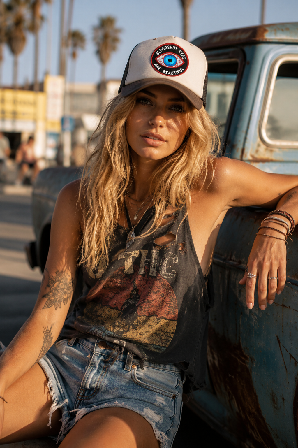 THC Bloodshot Patch displayed on the front of a trucker hat worn at the beach, featuring a bold embroidered blue eye with red and white detailing