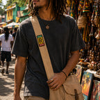 THC Rollin Rasta Patch displayed vertically on the strap of a natural tan canvas crossbody satchel worn by a young musician at an outdoor street market, featuring a reggae-inspired embroidered design