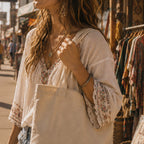 THC 420 Sun Patch displayed on a natural canvas tote bag carried by a young bohemian woman on the Venice Beach boardwalk, featuring a retro embroidered 420 sun design in yellow, orange, blue, and white