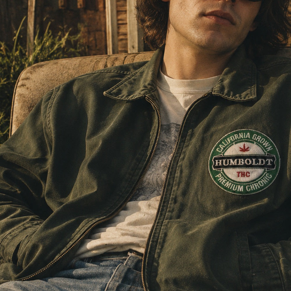 THC Humboldt Patch displayed on the chest of an olive canvas jacket worn by a laid-back musician outside a rustic cabin