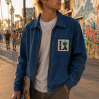 THC Leaf LA Patch displayed on the chest pocket of a blue canvas jacket worn by a young skateboarder on the Venice Beach boardwalk, featuring an embroidered cannabis leaf in a classic Los Angeles-inspired design