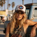 THC Bloodshot Patch displayed on the front of a trucker hat worn at the beach, featuring a bold embroidered blue eye with red and white detailing