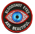 THC Bloodshot Patch featuring an embroidered blue eye with red and white detailing and the phrase “Bloodshot Eyes Are Beautiful” on a black circular background.