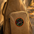 Brown guitar case with a patch on a stone surface