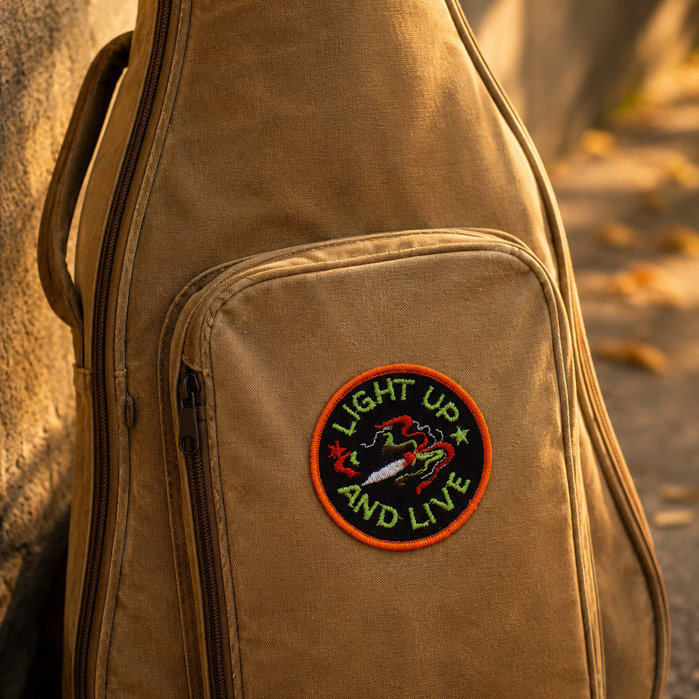 Brown guitar case with a patch on a stone surface