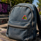 THC Recycle Leaf patch sewn onto faded denim backpack with outdoor urban setting