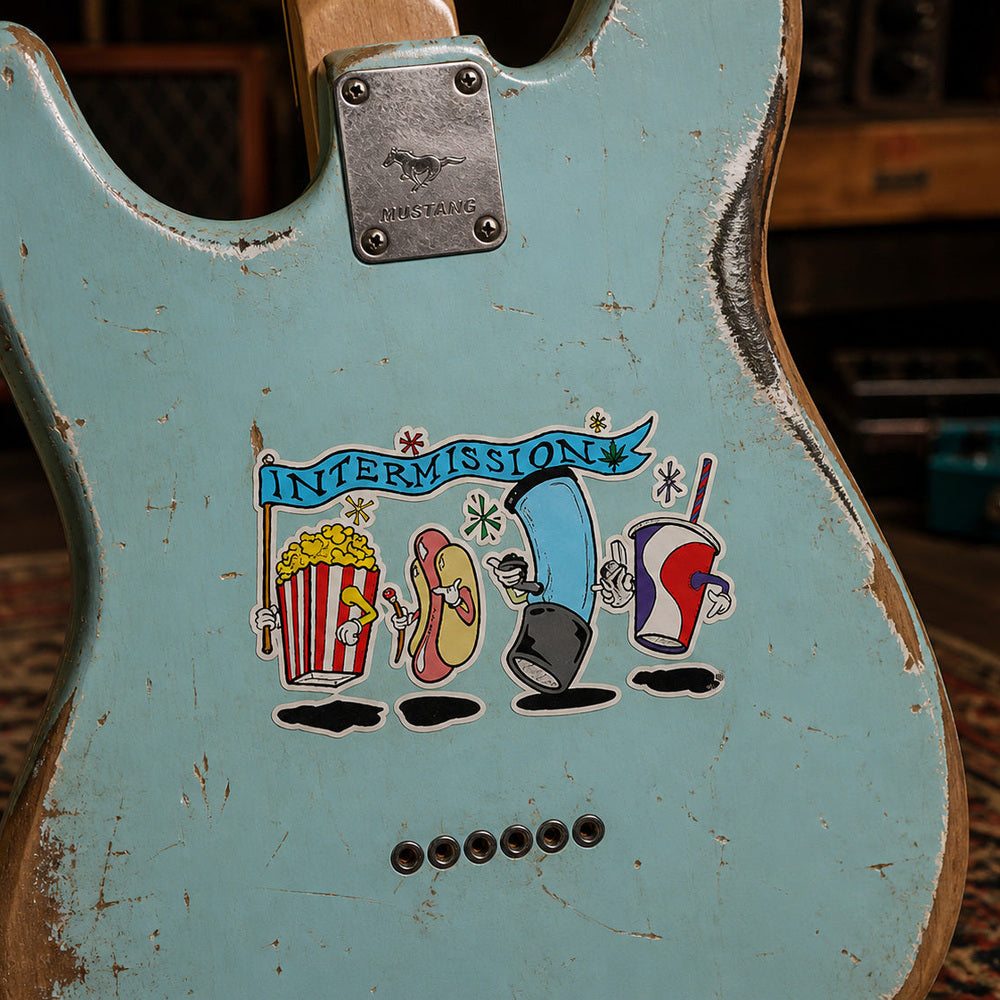THC Intermission sticker on worn robin’s egg blue Mustang guitar with chipped paint and studio background