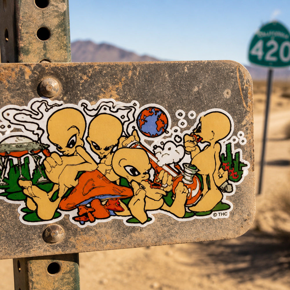 THC Alien Posse sticker placed on dusty metal road sign in desert landscape with sun and sand backdrop