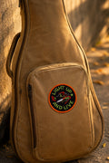 Brown guitar case with a patch on a stone surface