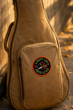 Brown guitar case with a patch on a stone surface