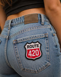 THC Route 420 patch on back pocket of light blue jeans on womens body with casual outdoor setting