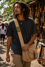 THC Rollin Rasta Patch displayed vertically on the strap of a natural tan canvas crossbody satchel worn by a young musician at an outdoor street market, featuring a reggae-inspired embroidered design